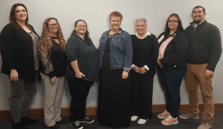 Group of adults pose and smile on a neutral backdrop