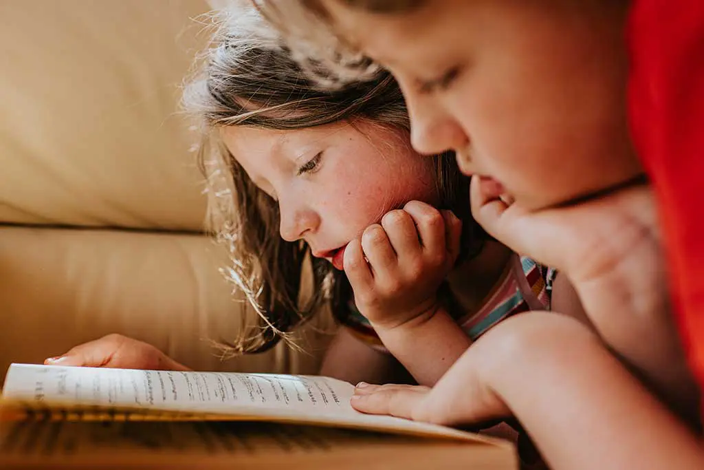 Two young children focused on reading a book
