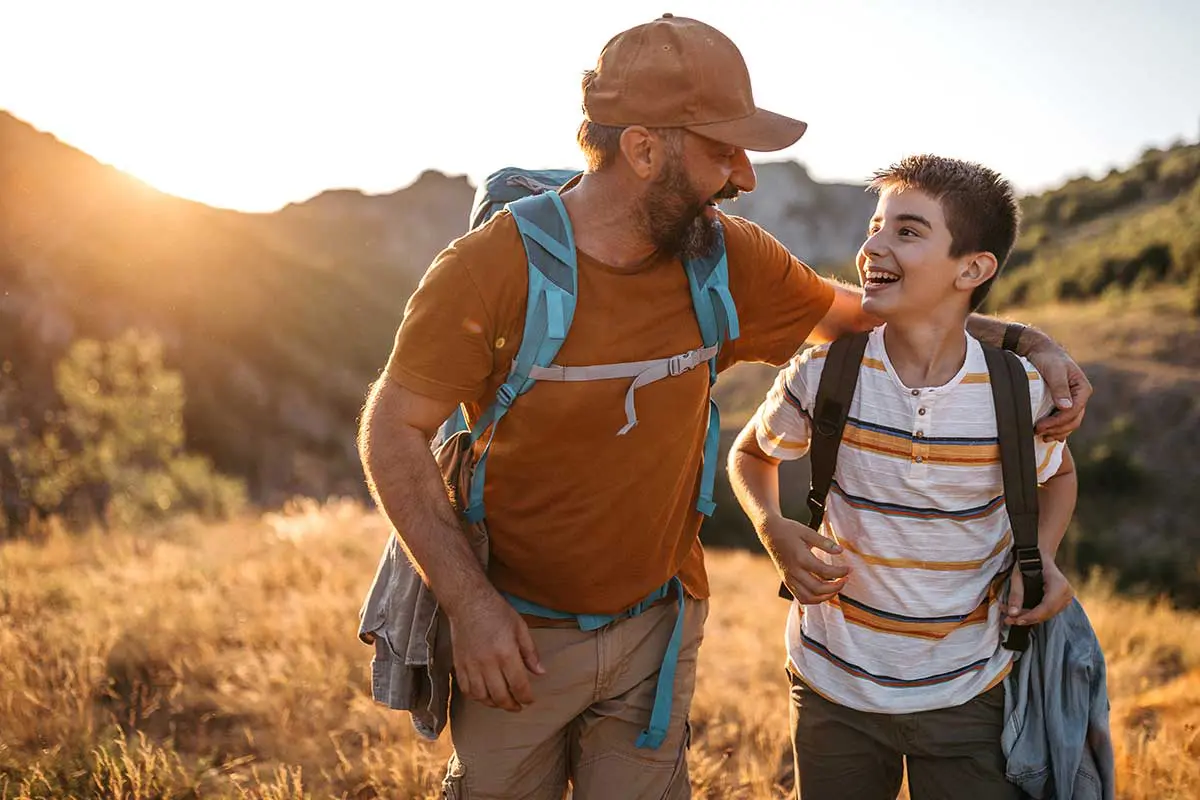 A happy father and son go on a hike on a bright and sunny day