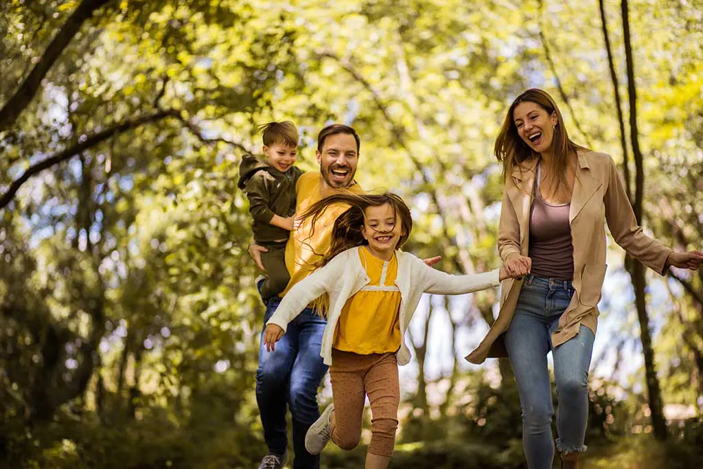 A happy family run and play while taking a walk in the woods