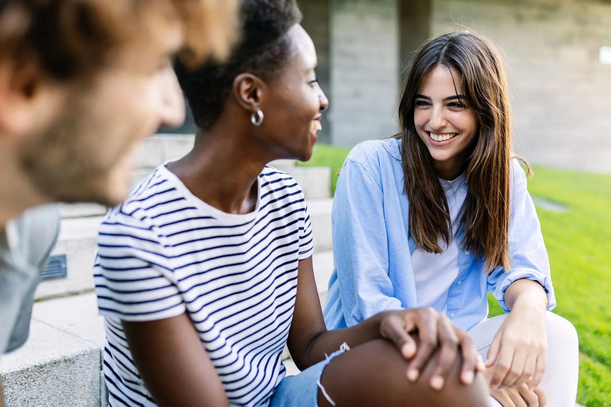Three teens smile while spending time together at a park outdoors