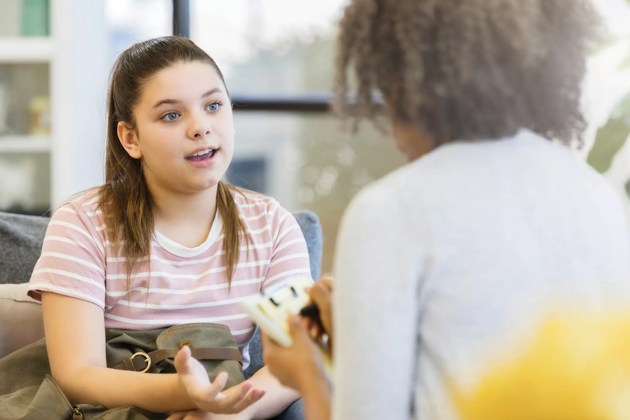 Pre-teen girl explains her problems to a female psychiatrist sitting opposite to her