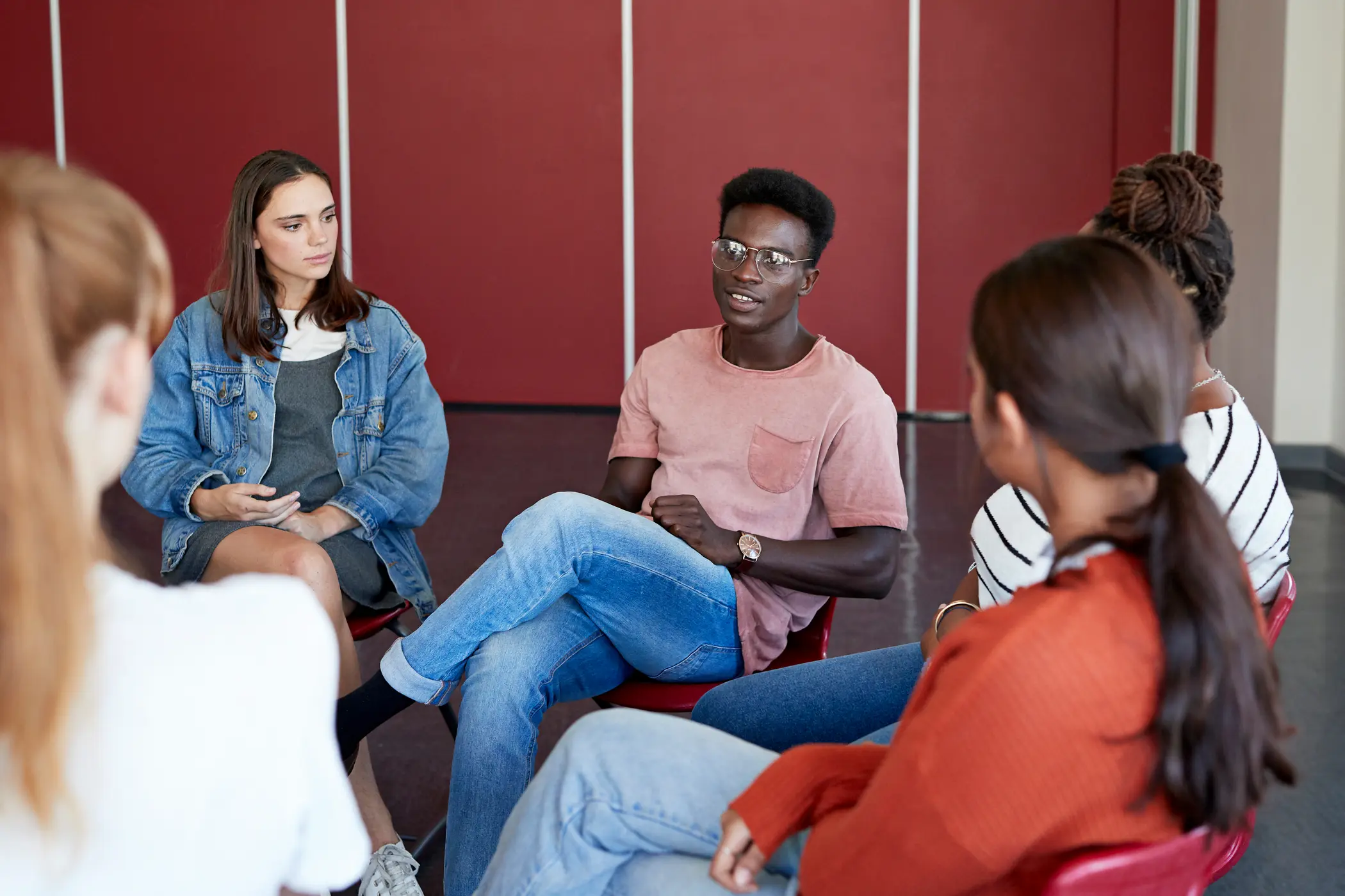 Group of teenagers sitting in a circle participating in group therapy