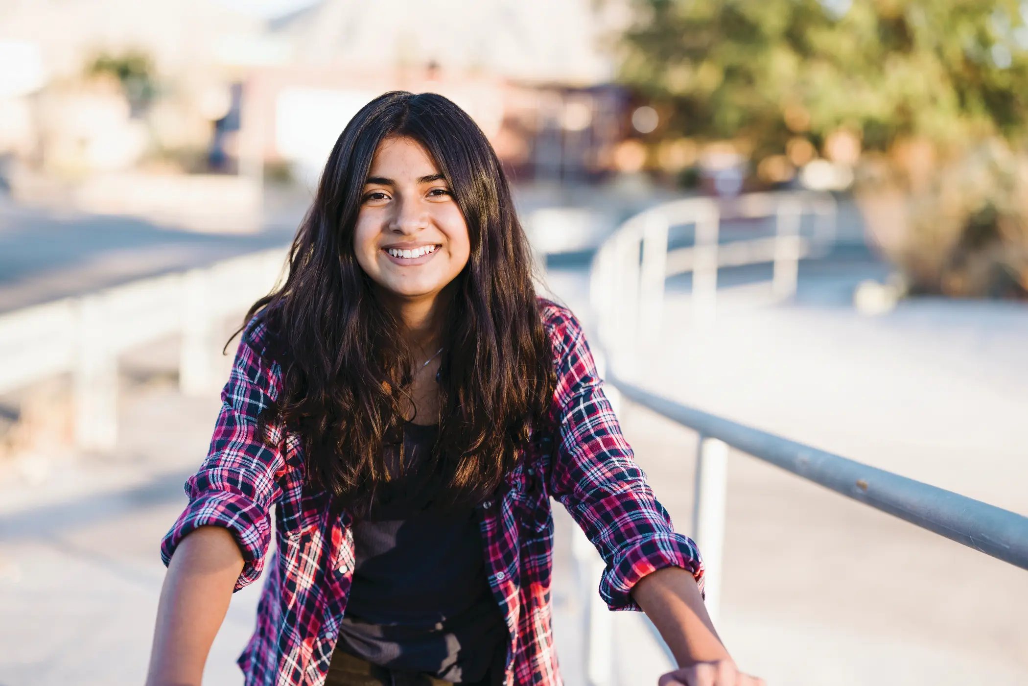 A teenage girl smiles while spending time in an urban park on a sunny day